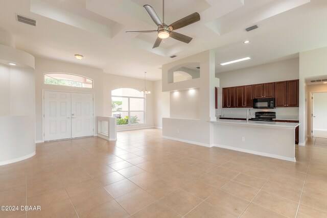 unfurnished living room featuring ceiling fan with notable chandelier, light tile patterned floors, and sink