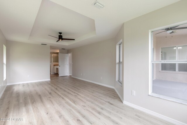 interior space featuring ceiling fan, a tray ceiling, and light hardwood / wood-style floors