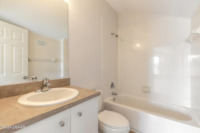 full bathroom featuring vanity, tiled shower / bath, toilet, and lofted ceiling