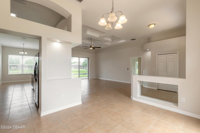 unfurnished room featuring ceiling fan with notable chandelier, a wealth of natural light, and light tile patterned flooring