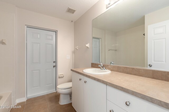 bathroom featuring toilet, vanity, a textured ceiling, and tile patterned floors