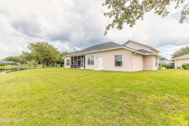 back of property featuring a sunroom, a yard, and a water view