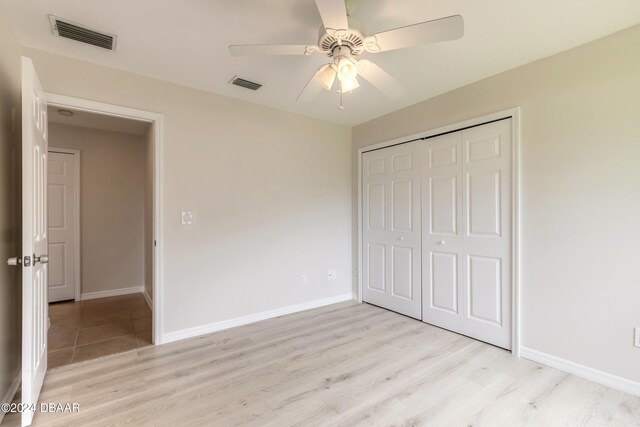 unfurnished bedroom featuring light hardwood / wood-style floors, ceiling fan, and a closet