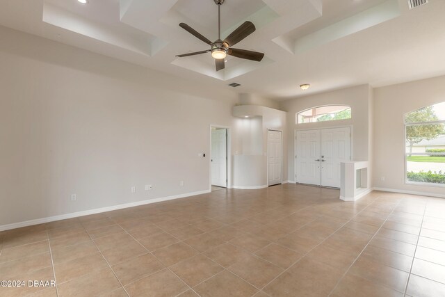 unfurnished room with ceiling fan, light tile patterned floors, and a raised ceiling