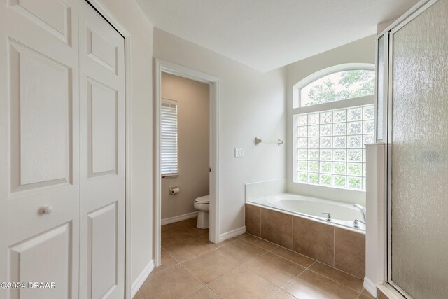 bathroom with tile patterned floors, toilet, and separate shower and tub