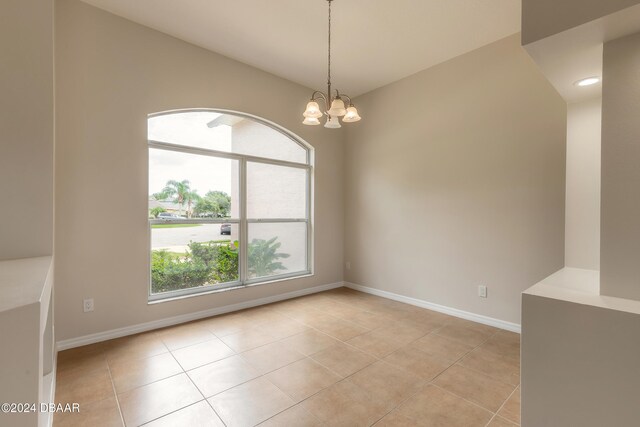 tiled empty room with a notable chandelier