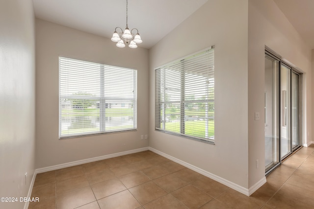 unfurnished room with a chandelier and light tile patterned floors