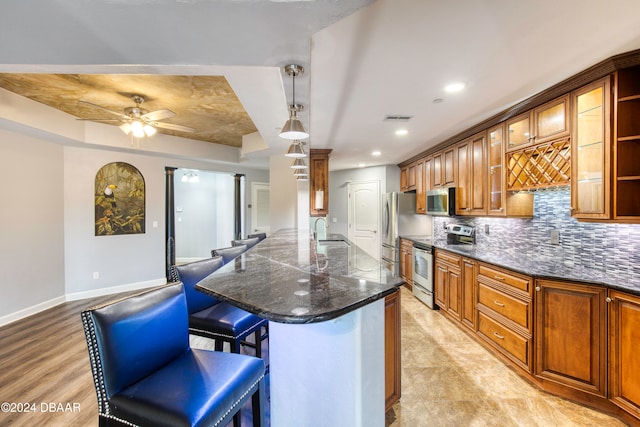 kitchen featuring light hardwood / wood-style floors, hanging light fixtures, sink, a breakfast bar, and appliances with stainless steel finishes