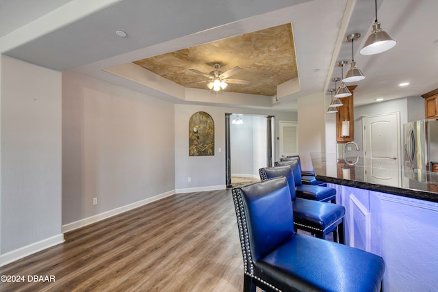 kitchen with stainless steel fridge with ice dispenser, a raised ceiling, pendant lighting, hardwood / wood-style flooring, and ceiling fan