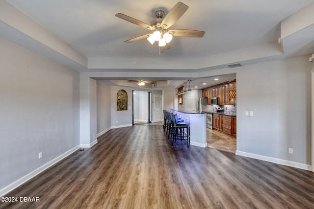 kitchen with dark wood-type flooring, a kitchen island, ceiling fan, and a breakfast bar area