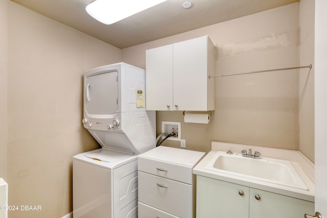 washroom featuring cabinets, stacked washer and clothes dryer, and sink