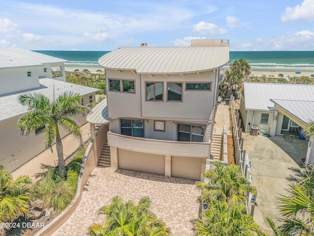 view of front of property featuring a garage, a view of the beach, and a water view