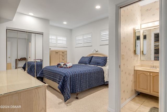 bedroom featuring a closet, sink, and light carpet