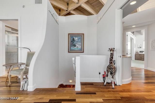 stairs with hardwood / wood-style floors, beamed ceiling, and wooden ceiling