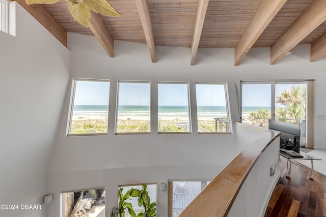 interior space featuring a view of the beach, a water view, ceiling fan, beam ceiling, and wood ceiling