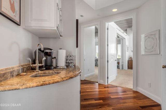 kitchen featuring white cabinetry, dark hardwood / wood-style flooring, sink, and light stone counters