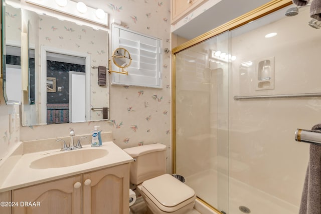 bathroom with vanity, toilet, and a shower with door