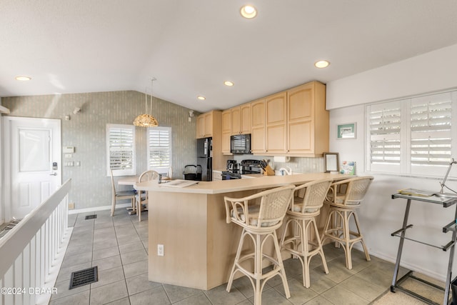 kitchen with a kitchen bar, kitchen peninsula, black appliances, pendant lighting, and light brown cabinetry