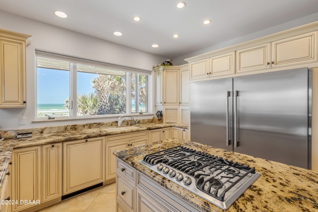 kitchen featuring light tile patterned floors, appliances with stainless steel finishes, light stone counters, and cream cabinetry