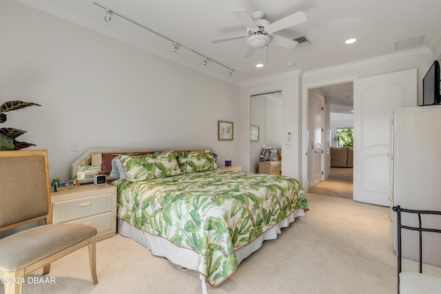 carpeted bedroom with ceiling fan, a closet, track lighting, and ornamental molding