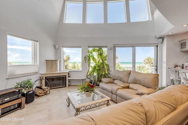 living room with a high ceiling, a water view, a wealth of natural light, and light tile patterned flooring