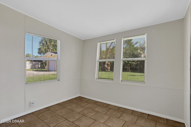 unfurnished room featuring lofted ceiling and tile patterned floors