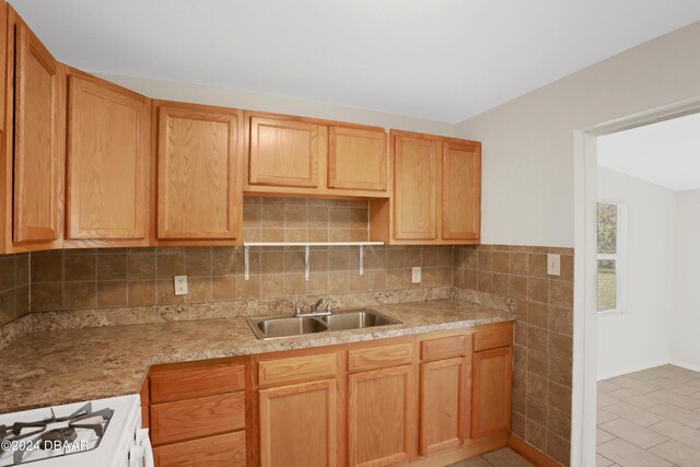 kitchen featuring tasteful backsplash, white range with gas cooktop, light tile patterned flooring, sink, and vaulted ceiling