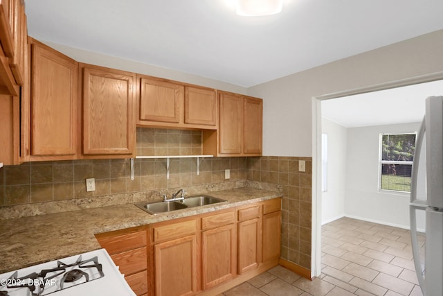 kitchen with white cooktop, decorative backsplash, refrigerator, and sink