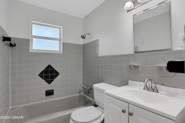 full bathroom featuring tiled shower / bath, vanity, tile walls, and toilet