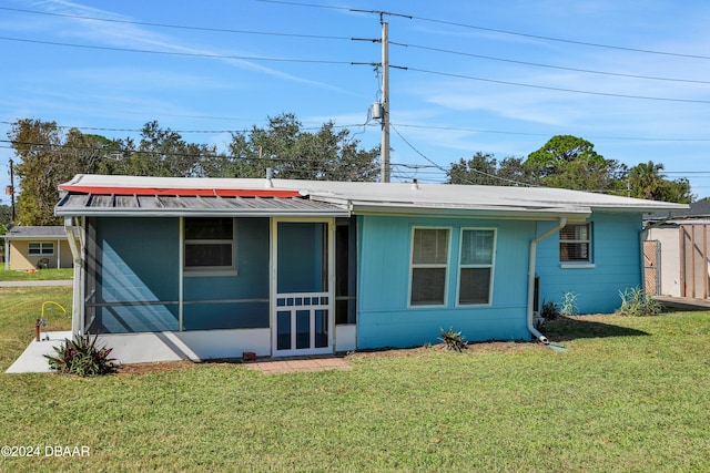 back of house featuring a sunroom and a lawn