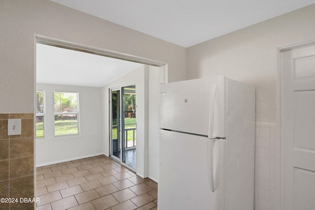 kitchen with white refrigerator, tile patterned flooring, and lofted ceiling