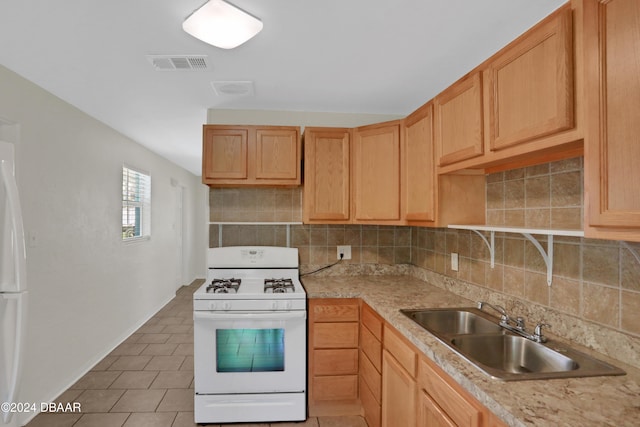 kitchen with tasteful backsplash, light brown cabinetry, white appliances, and sink