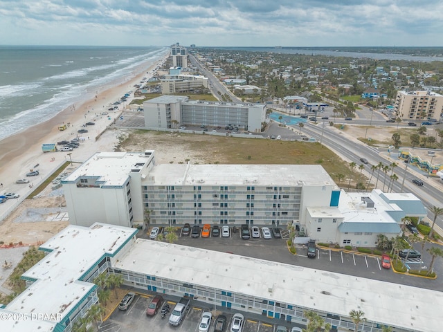 drone / aerial view featuring a water view, a view of city, and a view of the beach