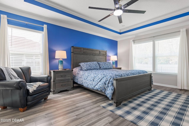 bedroom with crown molding, baseboards, a raised ceiling, and wood finished floors