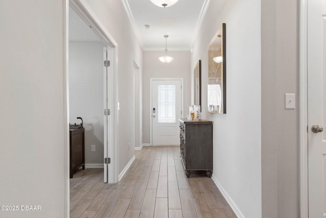 corridor featuring light wood-style floors, baseboards, and crown molding