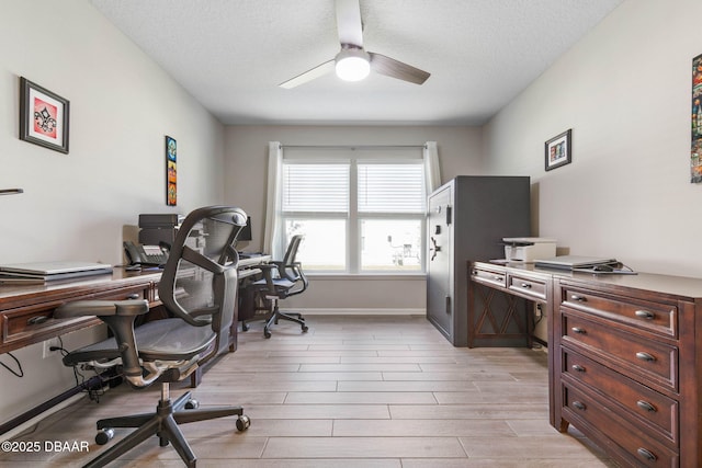 office space with light wood-style floors, ceiling fan, baseboards, and a textured ceiling