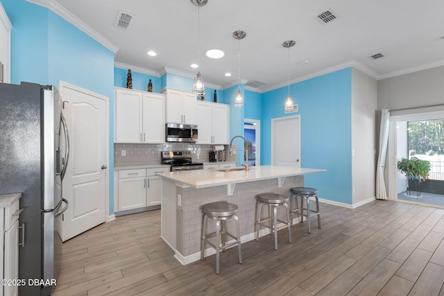 kitchen featuring visible vents, decorative backsplash, appliances with stainless steel finishes, light wood-style floors, and a sink