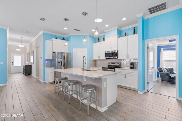 kitchen with light wood-style flooring, a sink, visible vents, appliances with stainless steel finishes, and tasteful backsplash