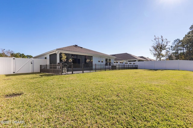 rear view of house featuring a sunroom, a fenced backyard, a gate, and a lawn