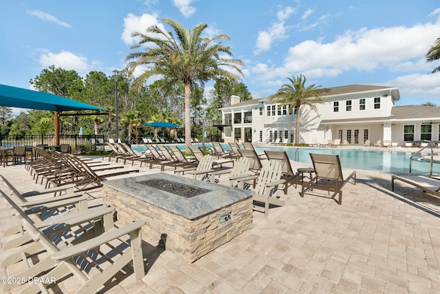 pool with an outdoor fire pit, a patio area, and fence