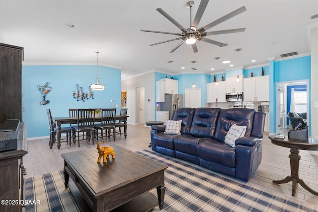 living room featuring light wood-style floors, baseboards, visible vents, and crown molding