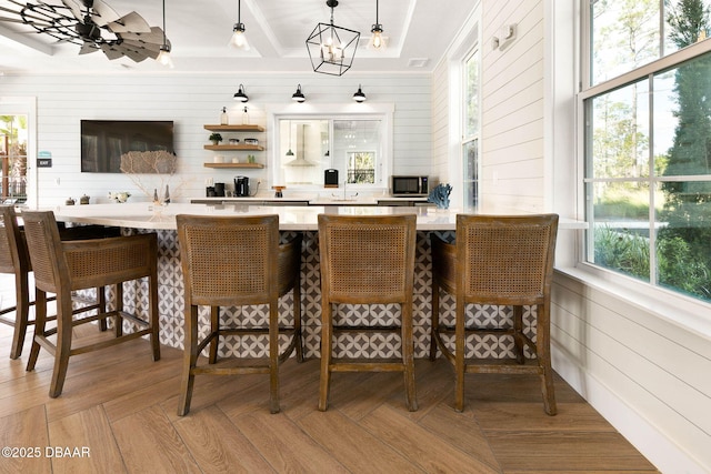 bar with wood walls, a sink, decorative light fixtures, and an inviting chandelier