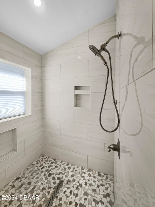 bathroom with lofted ceiling and a tile shower