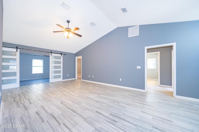 unfurnished living room with vaulted ceiling, ceiling fan, light hardwood / wood-style floors, a barn door, and built in shelves