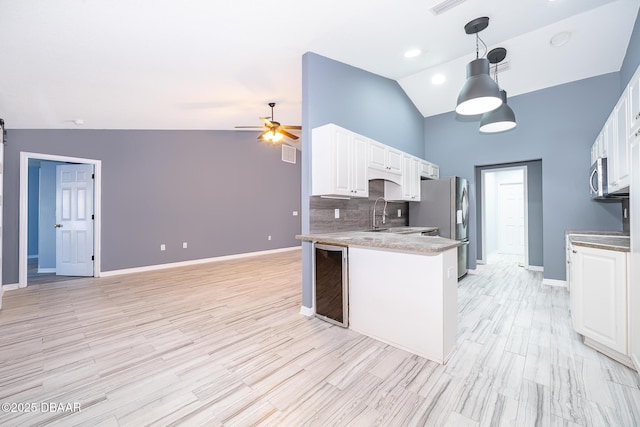 kitchen with white cabinets, tasteful backsplash, hanging light fixtures, wine cooler, and appliances with stainless steel finishes