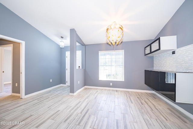 unfurnished dining area with lofted ceiling, a chandelier, and light hardwood / wood-style floors