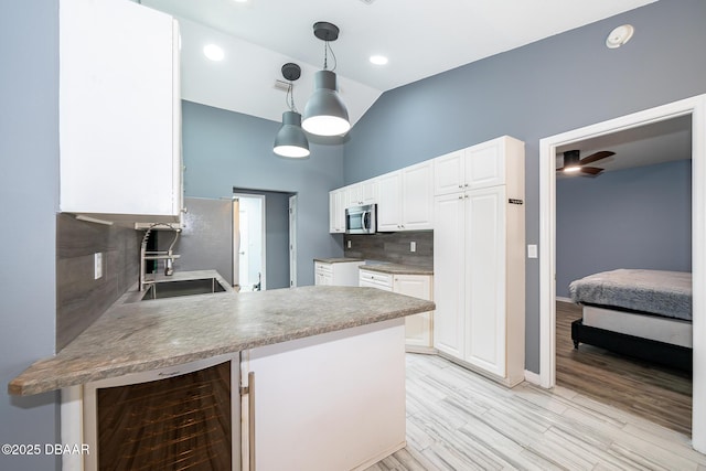 kitchen featuring beverage cooler, backsplash, kitchen peninsula, white cabinets, and lofted ceiling