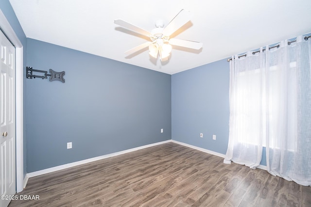 empty room with dark hardwood / wood-style flooring and ceiling fan