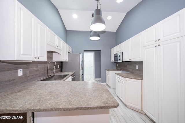 kitchen featuring decorative light fixtures, white cabinets, appliances with stainless steel finishes, and vaulted ceiling