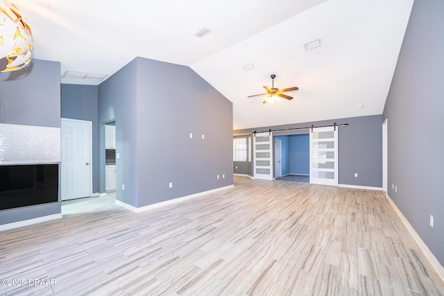 unfurnished living room featuring light hardwood / wood-style floors, lofted ceiling, a barn door, built in features, and ceiling fan